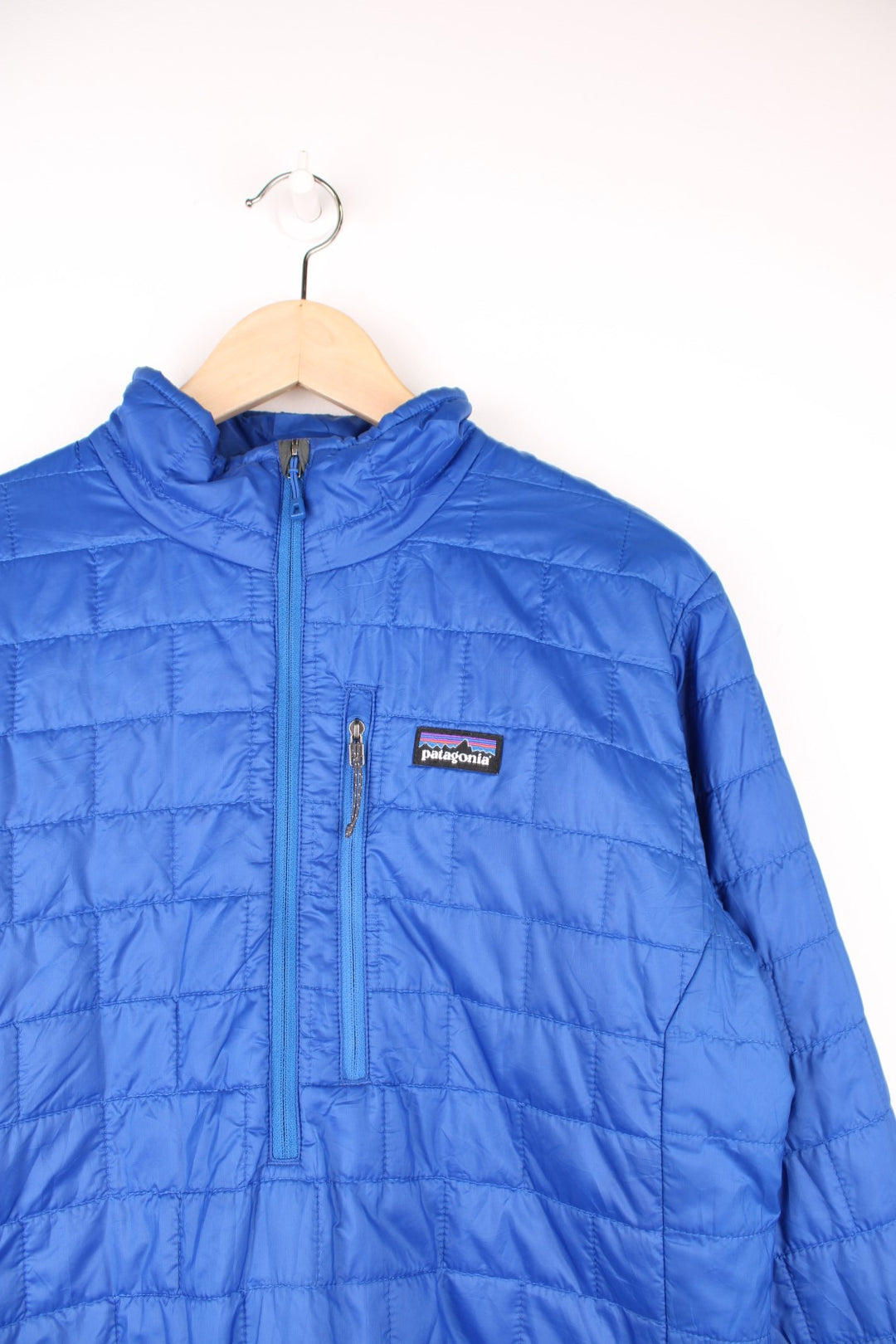 Patagonia Pullover Puffer Jacket in a blue colourway, half zip up with only one pocket on the chest, insulated, and has the logo embroidered on the front.