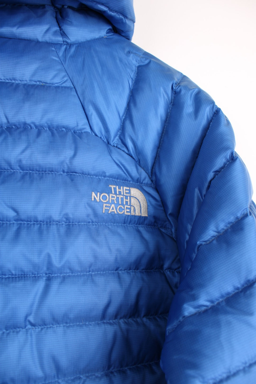 The North Face Puffer Jacket in a blue colourway, zip up with side pockets, hooded and has the logo embroidered on the front and back.