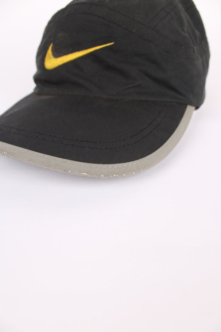 90's Nike cap in black, 100% polyester, adjustable strap, and yellow swoosh on the front.