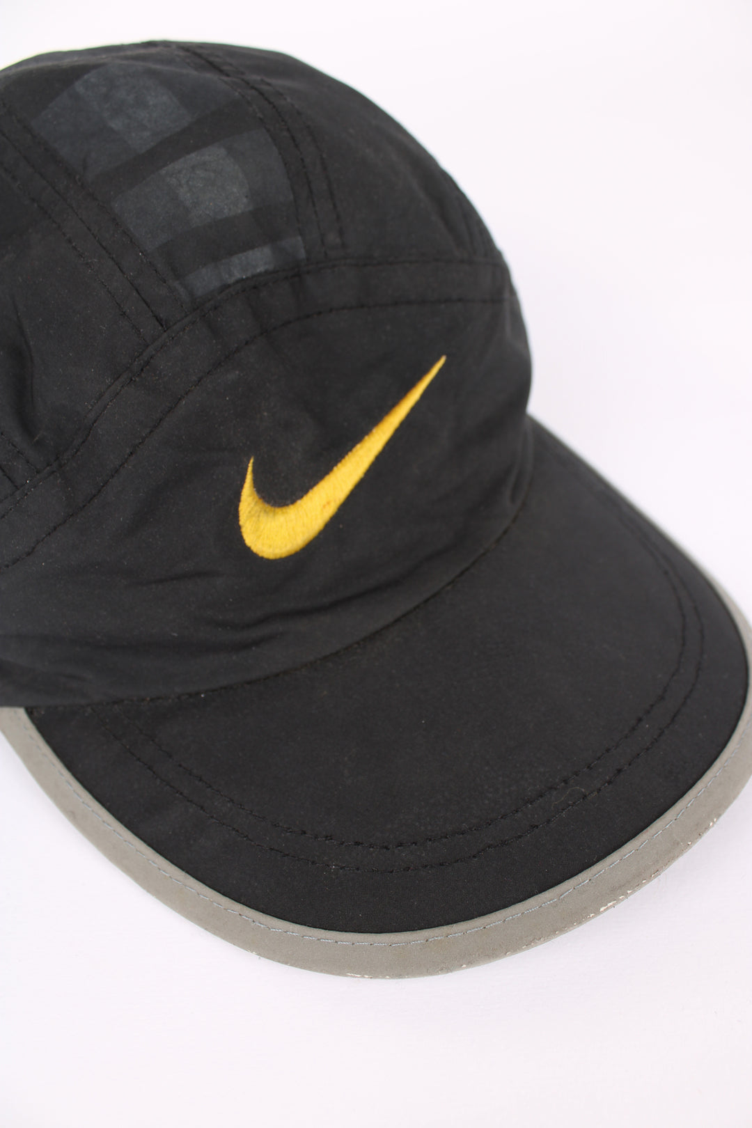 90's Nike cap in black, 100% polyester, adjustable strap, and yellow swoosh on the front.