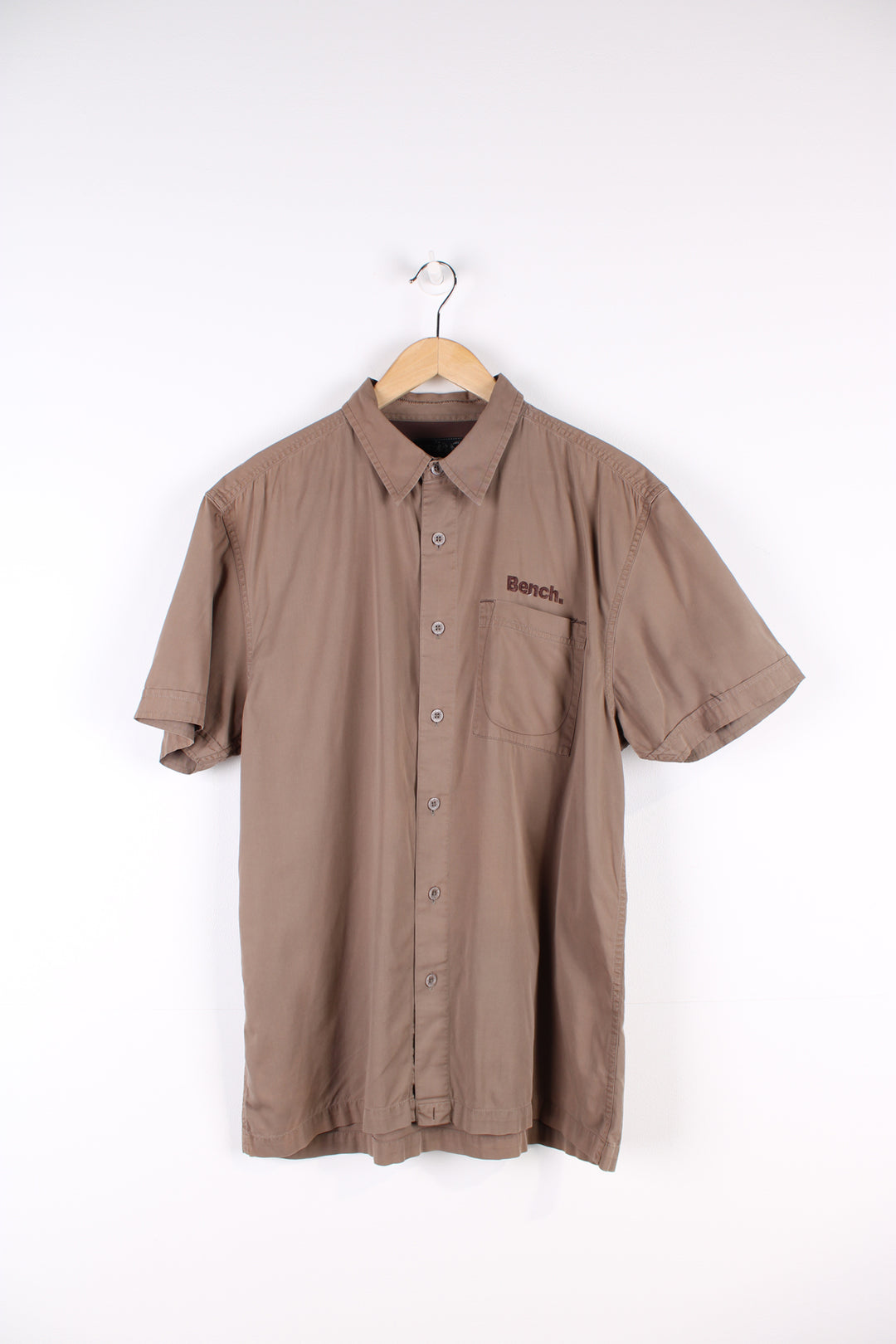 Y2K Bench brown short sleeved, cotton shirt. Features embroidered spell-out logo on the chest and across the back of the shoulders 