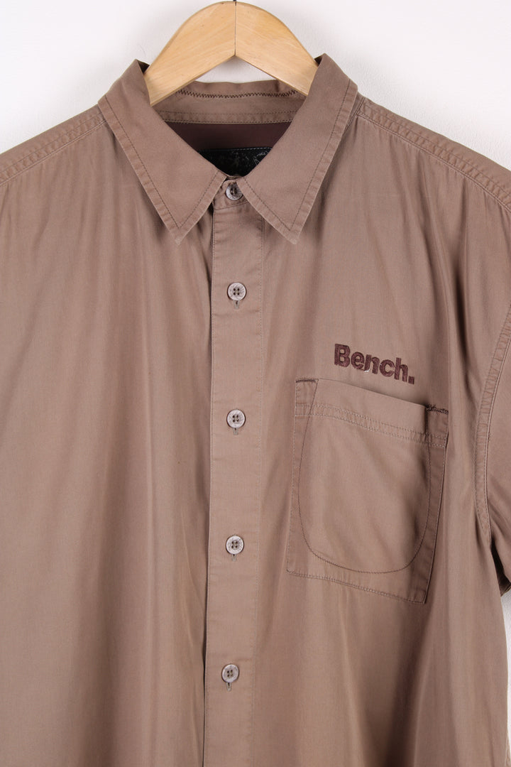 Y2K Bench brown short sleeved, cotton shirt. Features embroidered spell-out logo on the chest and across the back of the shoulders 