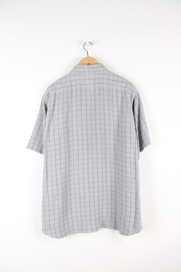 The North Face grey plaid, button up cotton shirt. Features velcro closure chest pocket and spell-out logo on the sleeve