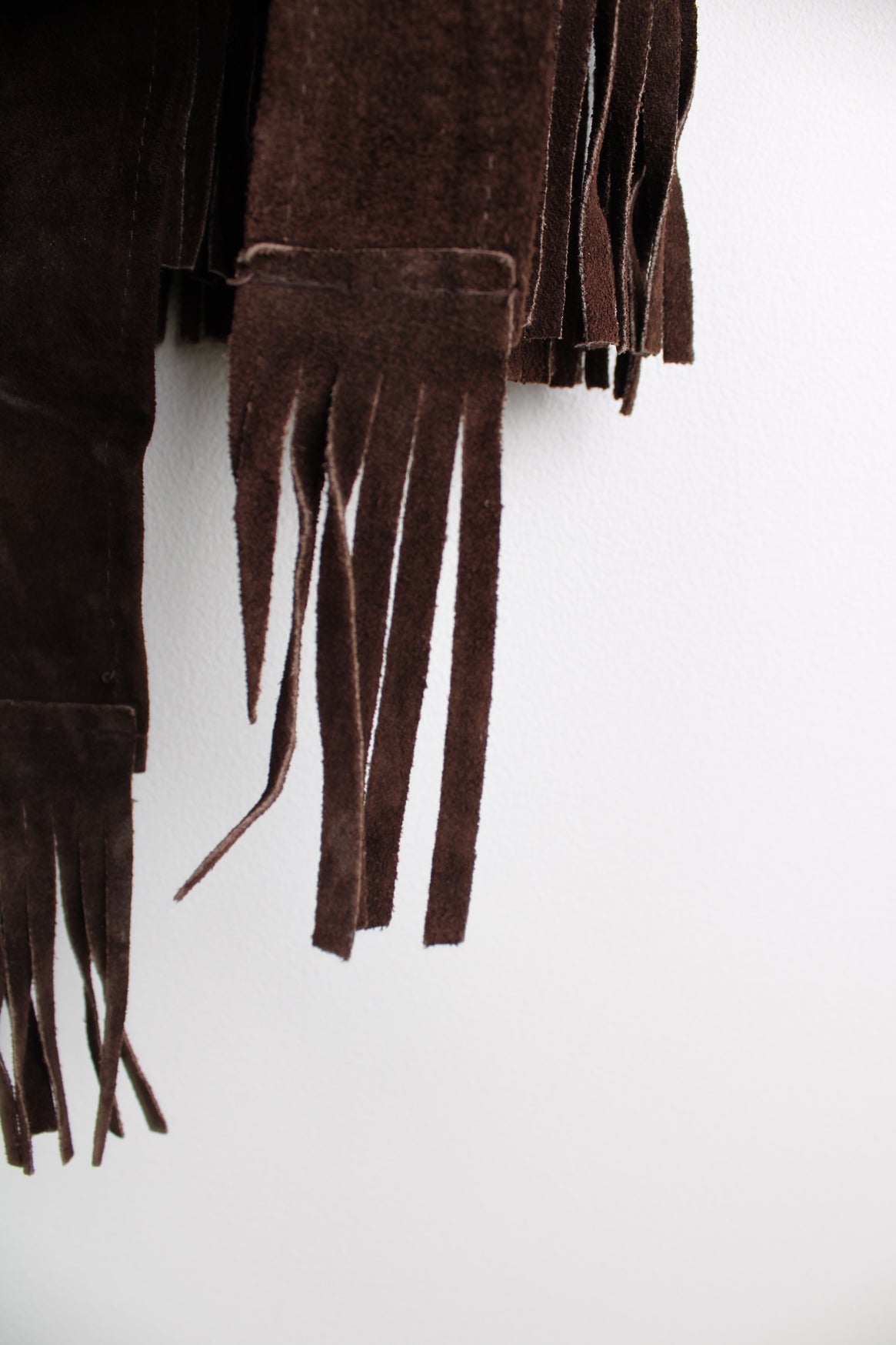 Vintage 1970s western style chocolate brown suede  jacket. Features belt, fringe detailing across the shoulders and down the sleeves and buttons for closure