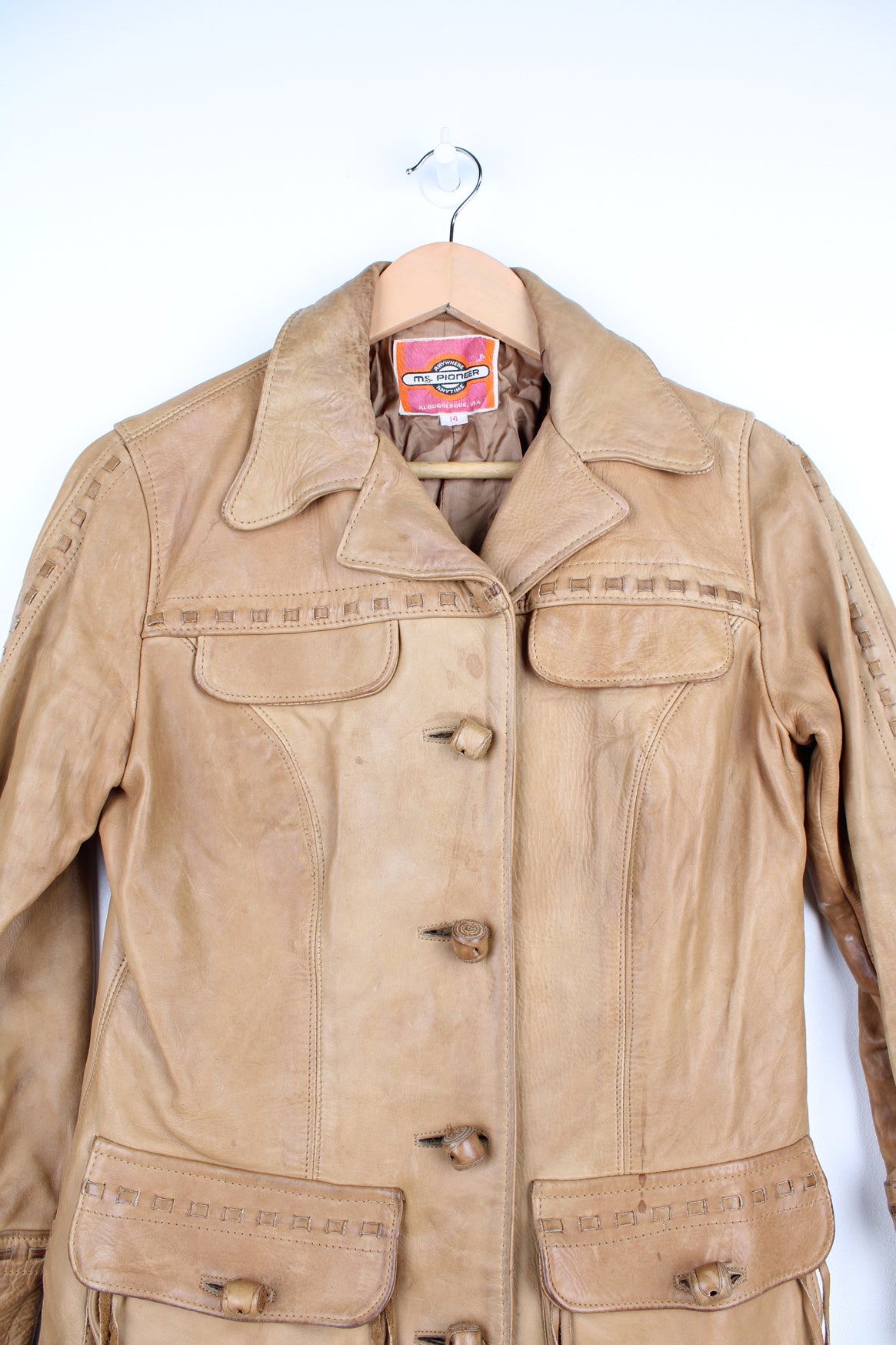 Vintage made in Albuquerque smooth tan leather jacket with fringe details on the pockets, raised stitched detailing on the sleeves and pockets and leather toggle buttons 