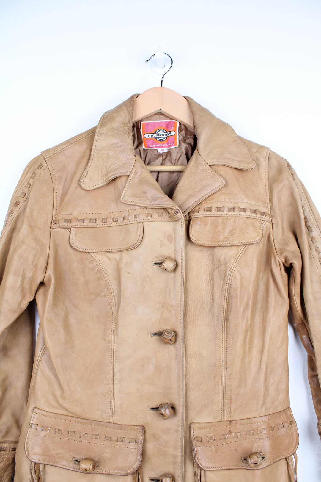 Vintage made in Albuquerque smooth tan leather jacket with fringe details on the pockets, raised stitched detailing on the sleeves and pockets and leather toggle buttons 