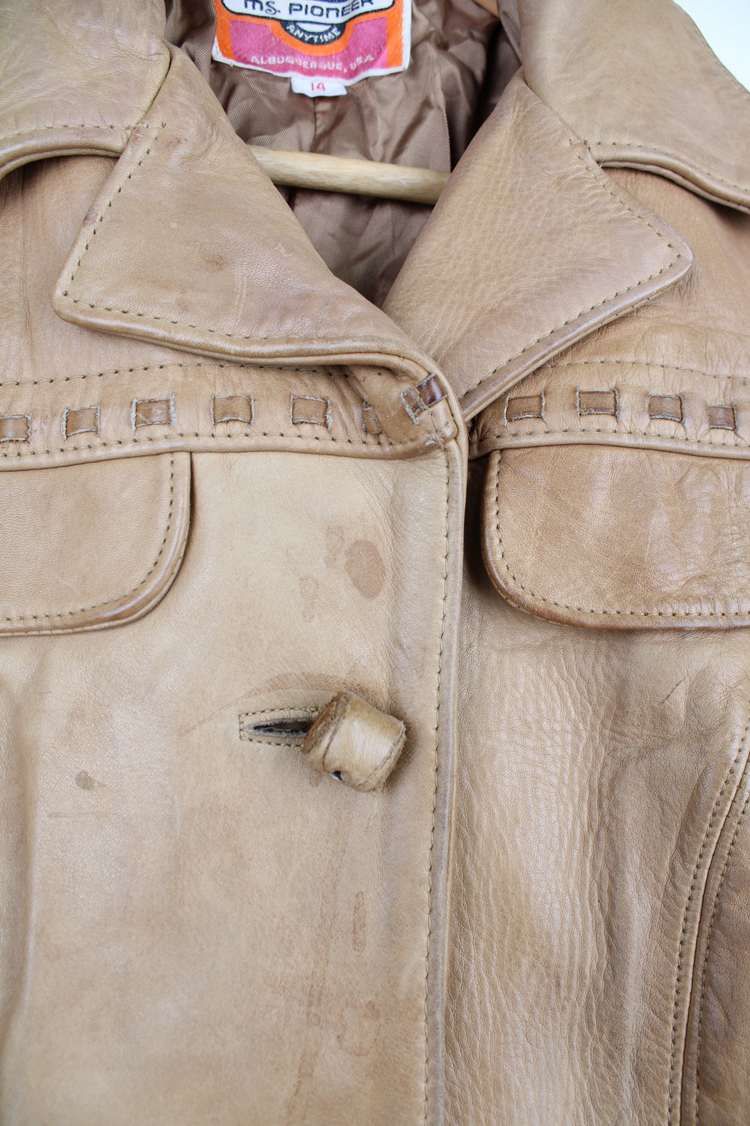 Vintage made in Albuquerque smooth tan leather jacket with fringe details on the pockets, raised stitched detailing on the sleeves and pockets and leather toggle buttons 