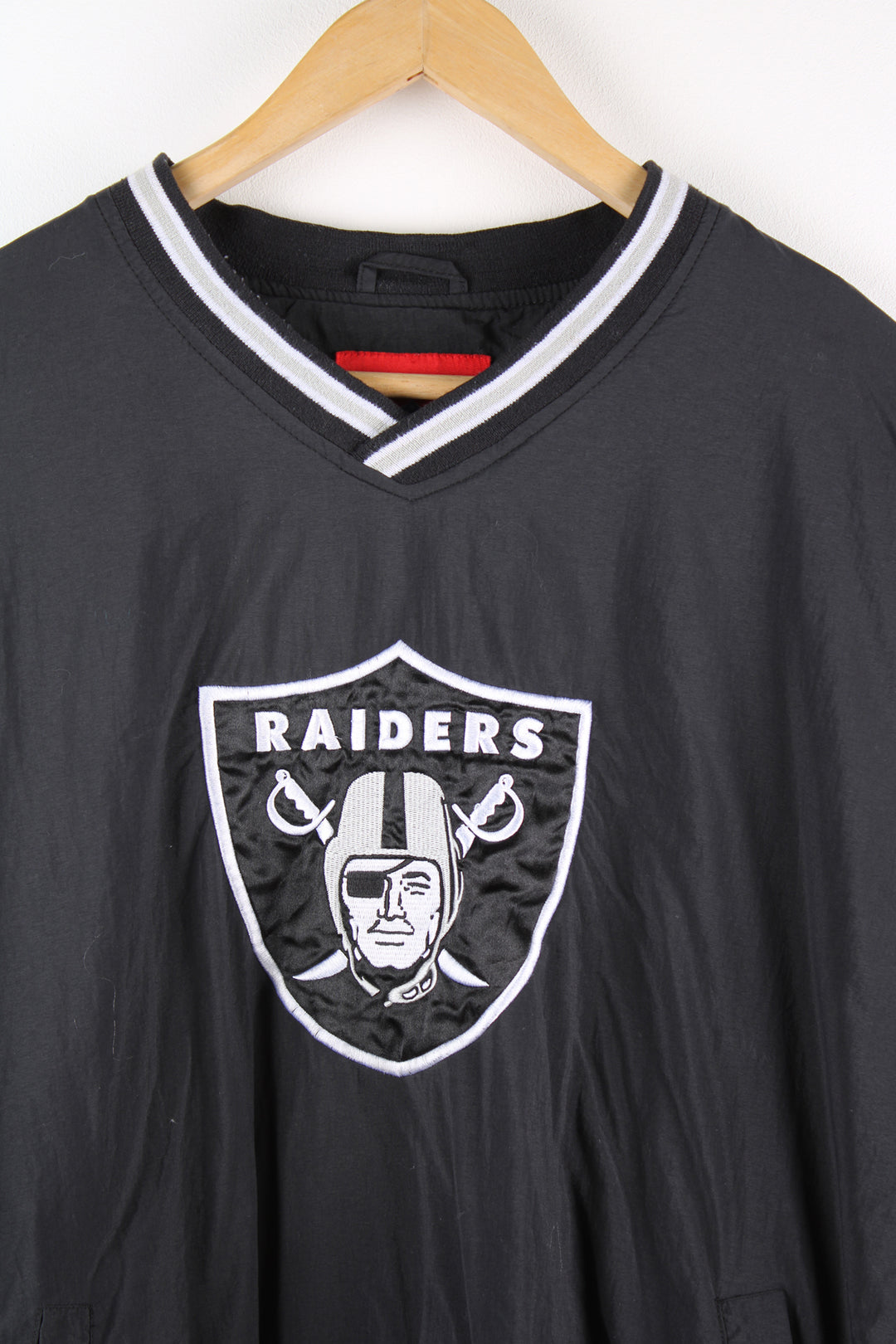 Vintage NFL Oakland Raiders drill top in black and grey team colourway, v neck, side pockets, and has logo embroidered on the front.