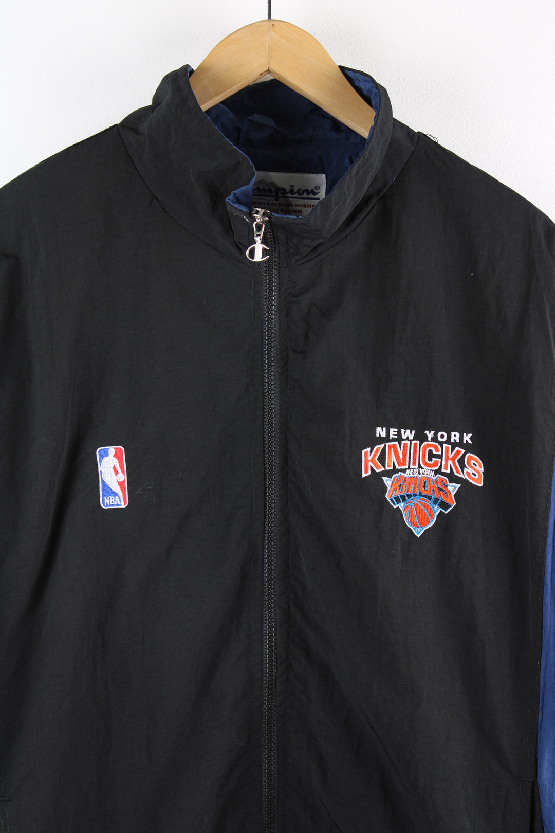 Vintage NBA New York Knicks, Champion windbreaker in a black and blue colourway, zip up with side pockets, has embroidered logos on the front, back and sleeves of the jacket. 