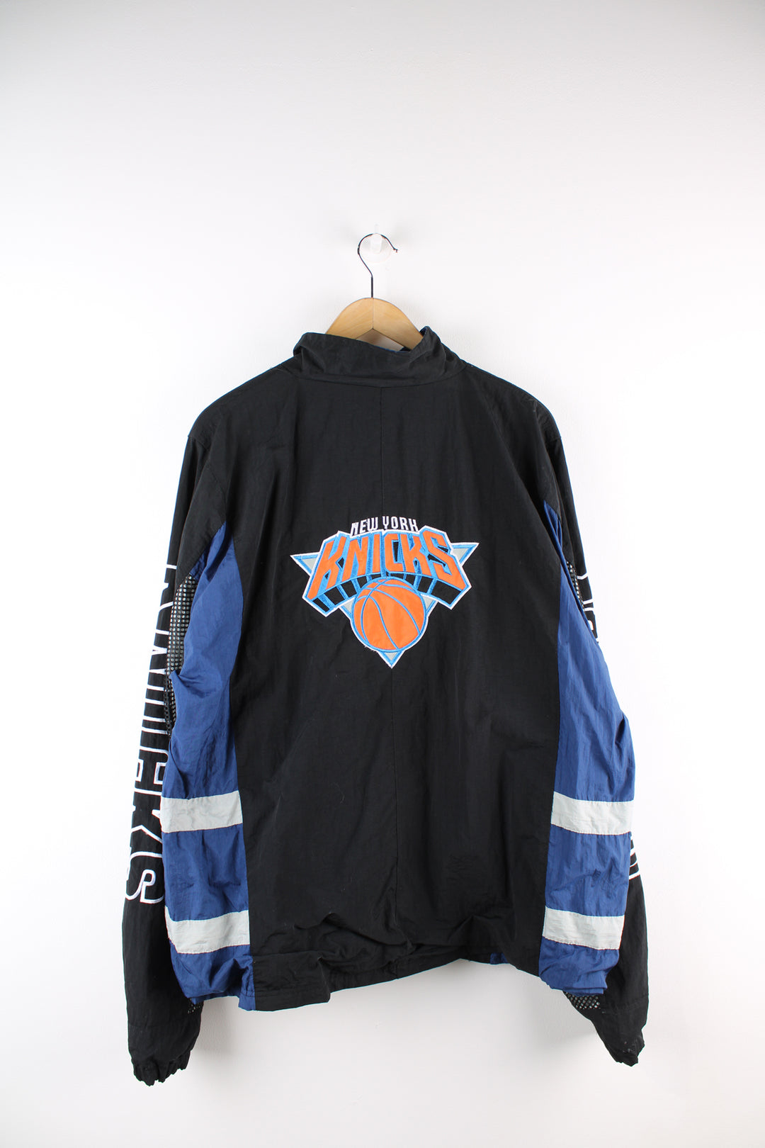 Vintage NBA New York Knicks, Champion windbreaker in a black and blue colourway, zip up with side pockets, has embroidered logos on the front, back and sleeves of the jacket. 