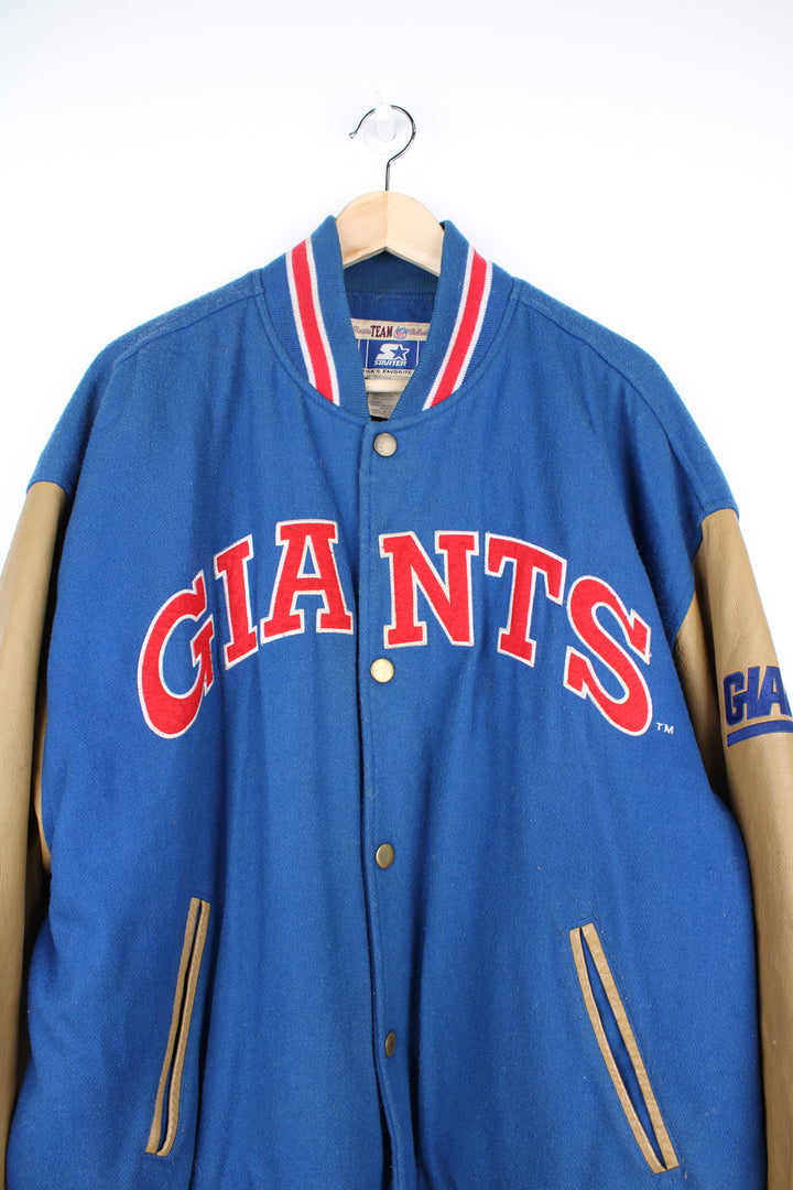 90's New York Giants varsity jacket with blue wool body and tan leather arms. Features embroidered logos on the arms and felt applique logo across the chest  good condition - Discoloration around the collar and scuffs to the leather on the arms and bobbling through out (see photos) Size in Label: Mens XL 