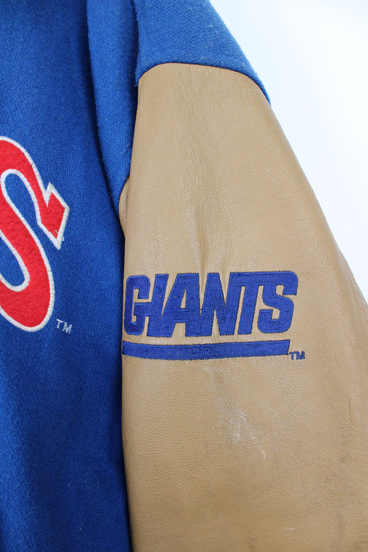 90's New York Giants varsity jacket with blue wool body and tan leather arms. Features embroidered logos on the arms and felt applique logo across the chest  good condition - Discoloration around the collar and scuffs to the leather on the arms and bobbling through out (see photos) Size in Label: Mens XL 