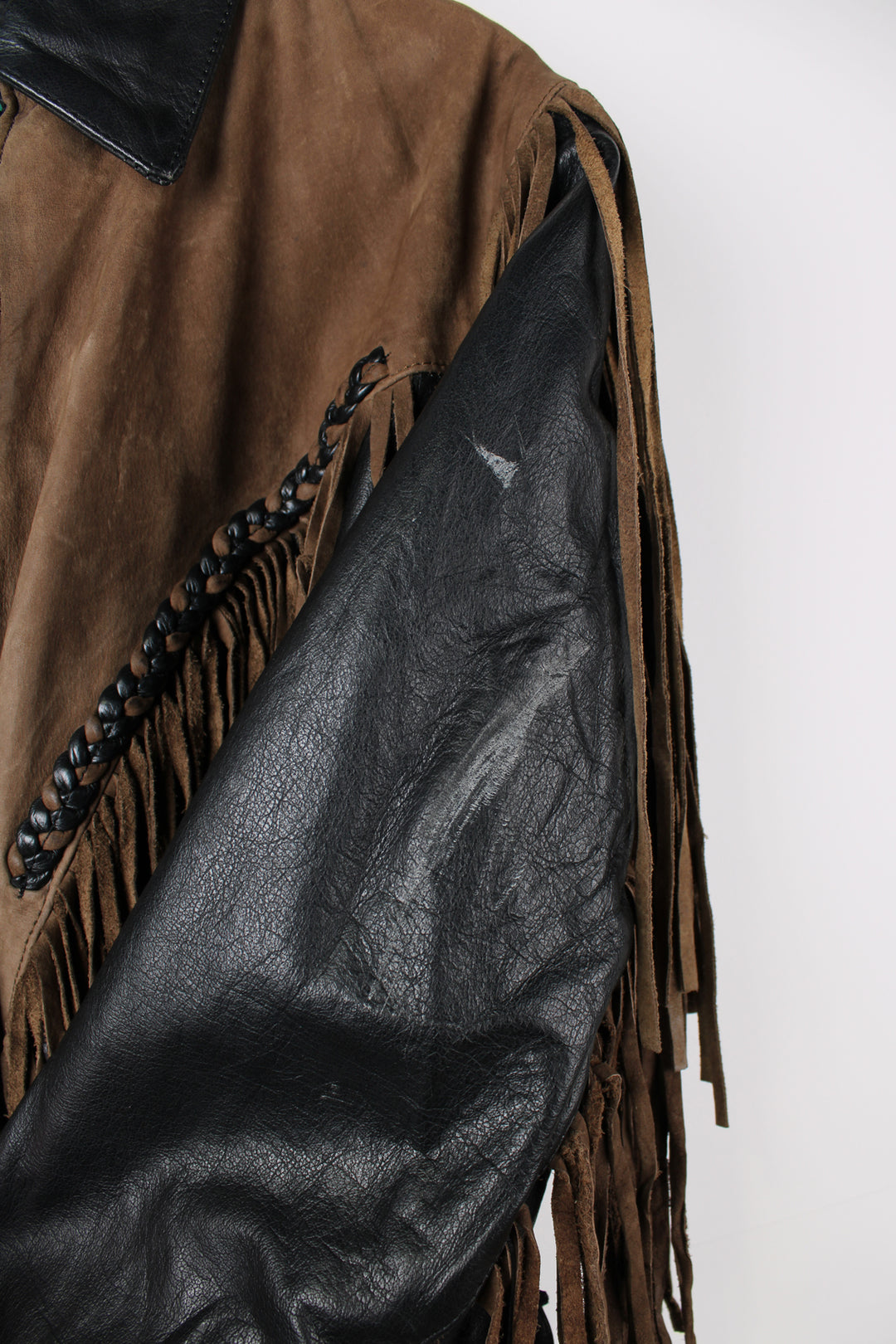 Vintage 80's black and brown fringe motorcycle leather jacket. Features a cropped fit, removable liner and fringe detailing on the sleeves and across the back of the shoulder