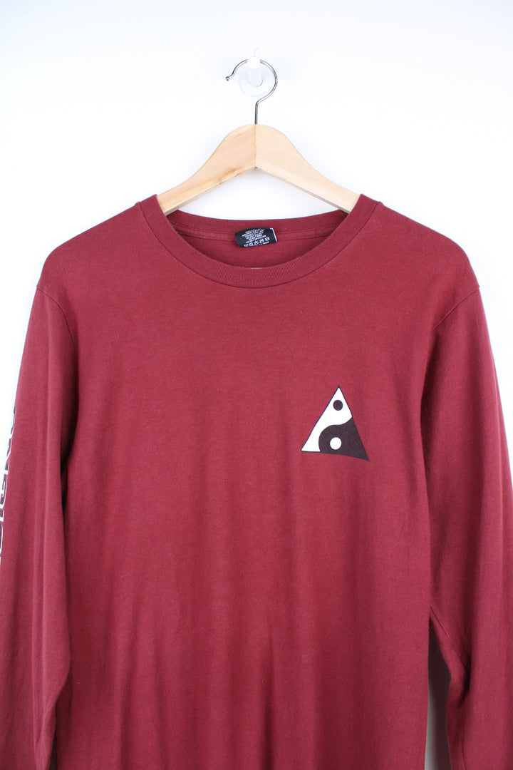 Maroon red Stussy long sleeved t-shirt with yin yang graphic on the front and spell-out graphic down the sleeve 