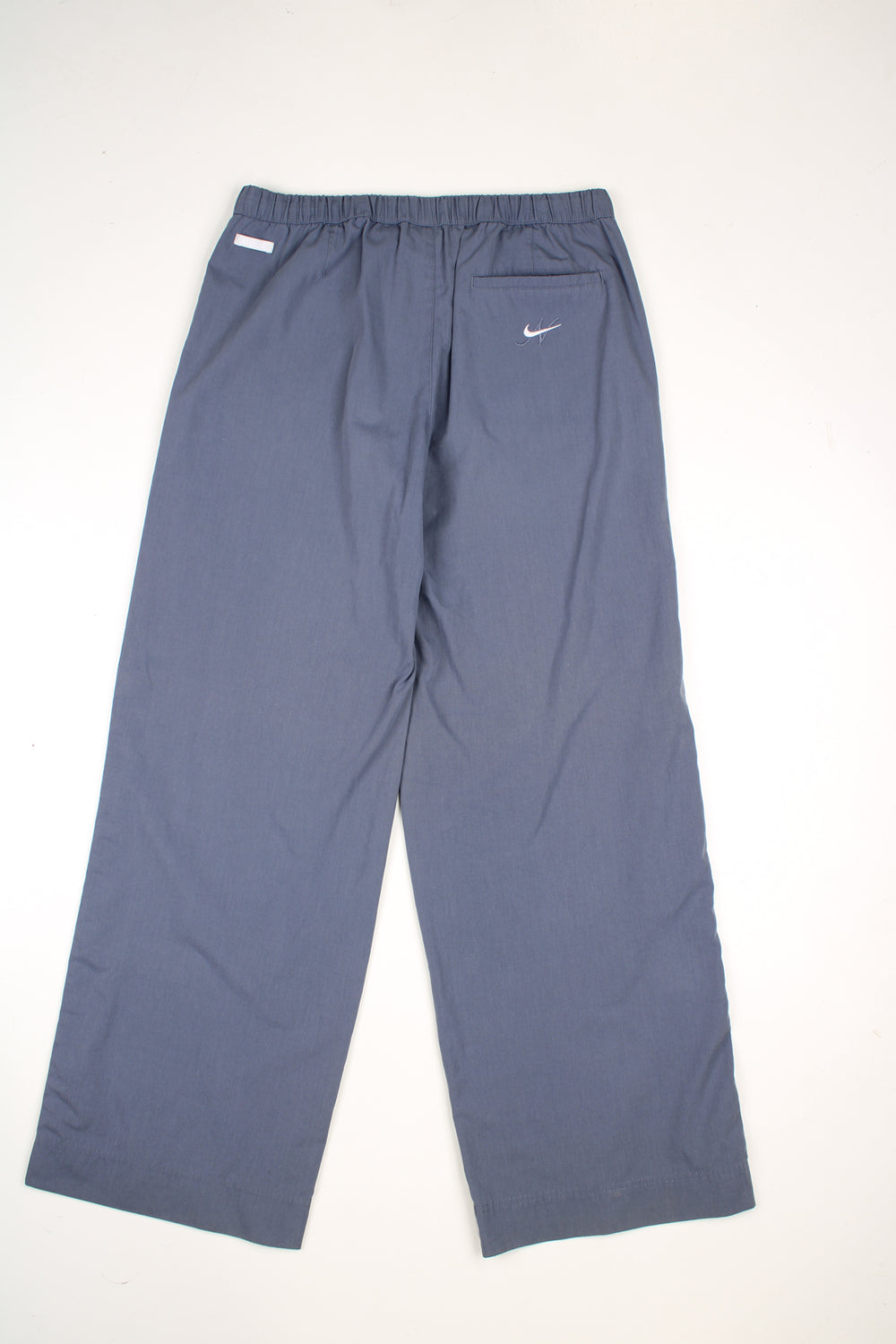 Vintage Nike tracksuit bottoms in a grey colourway, elasticated waist, multiple pockets, and has logo embroidered on the front.