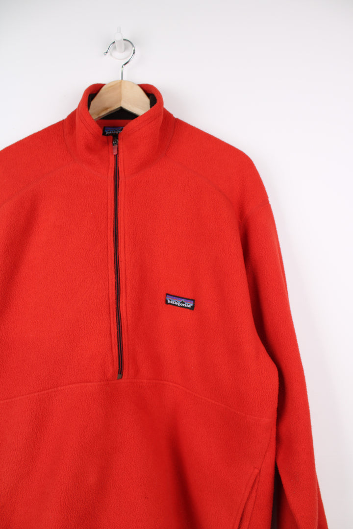 Patagonia Synchilla Fleece in a orange colourway, half zip up, big pouch pocket, and has logo embroidered on the front.