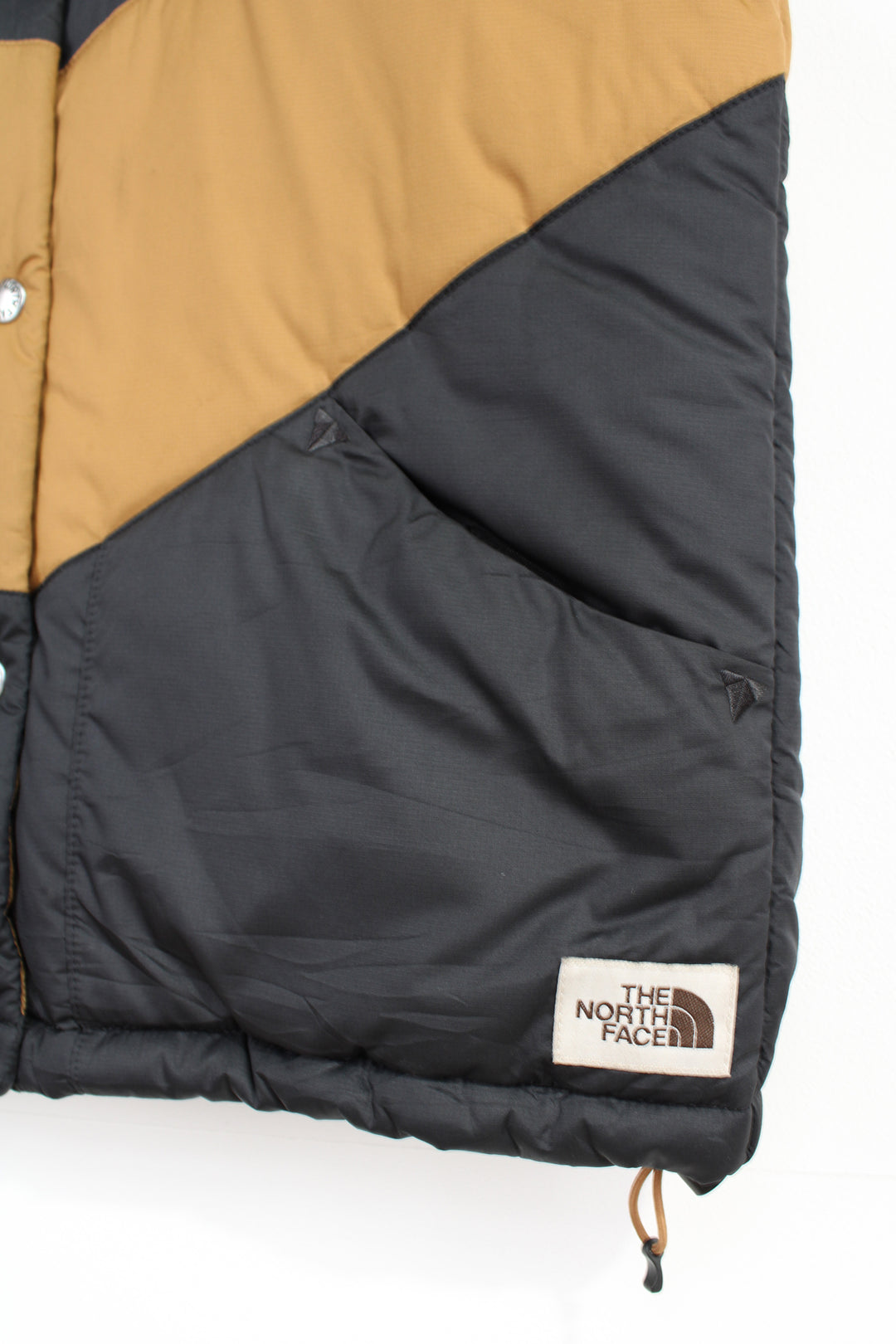 The North Face 'Sylvester' brown and black button up puffer gilet with embroidered logo on the hem