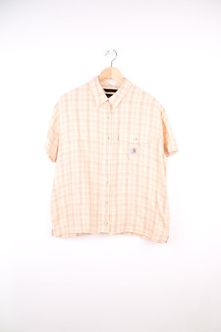 Carhartt Plaid Short Sleeve Shirt in a tan and red colourway, button up, cropped fit, has hidden side pockets, and also has the logo embroidered on the chest pocket.