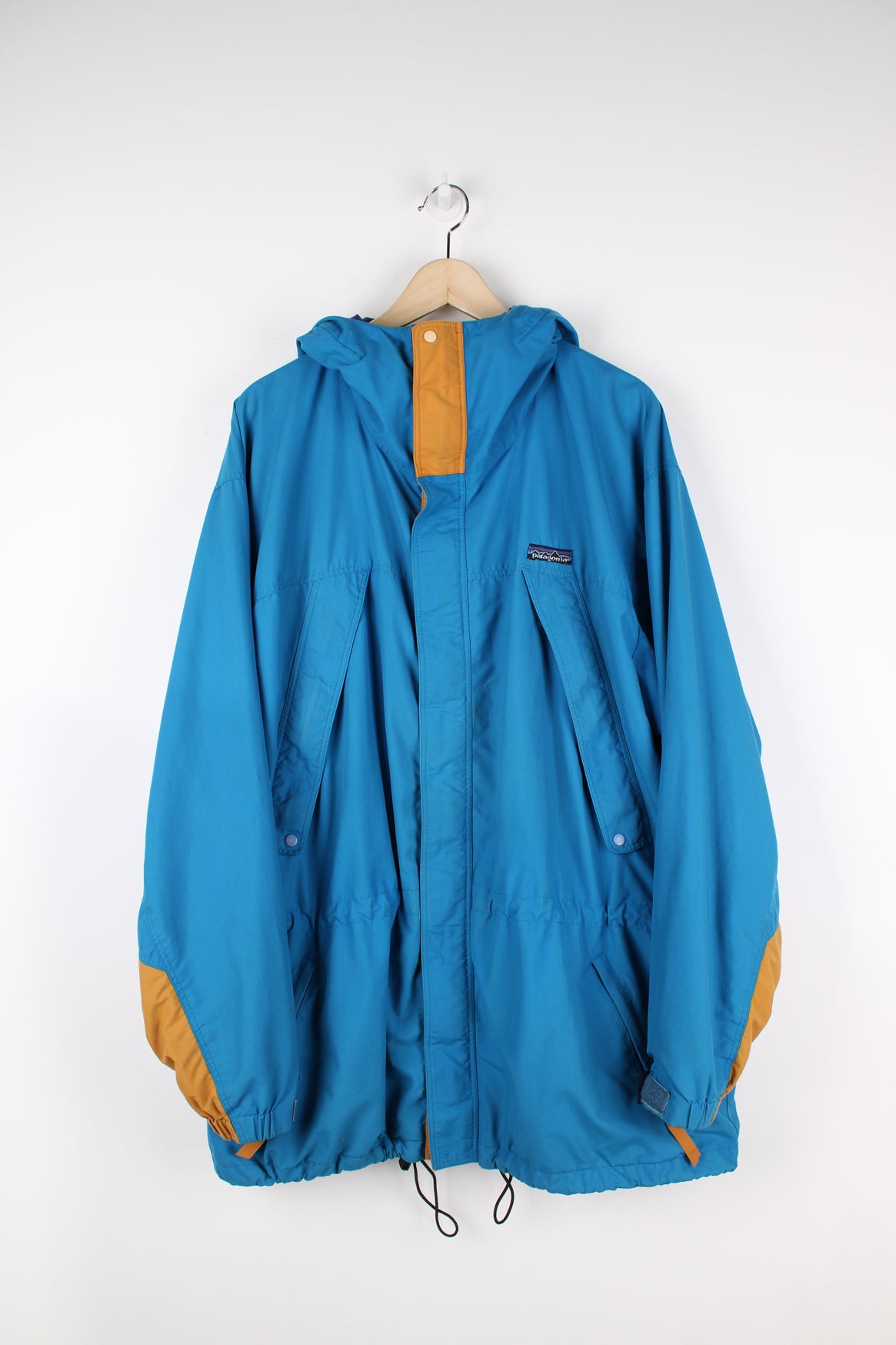 Patagonia Torrentshell outdoor jacket in blue, zip up, multiple pockets, hooded and has embroidered logo on the front.