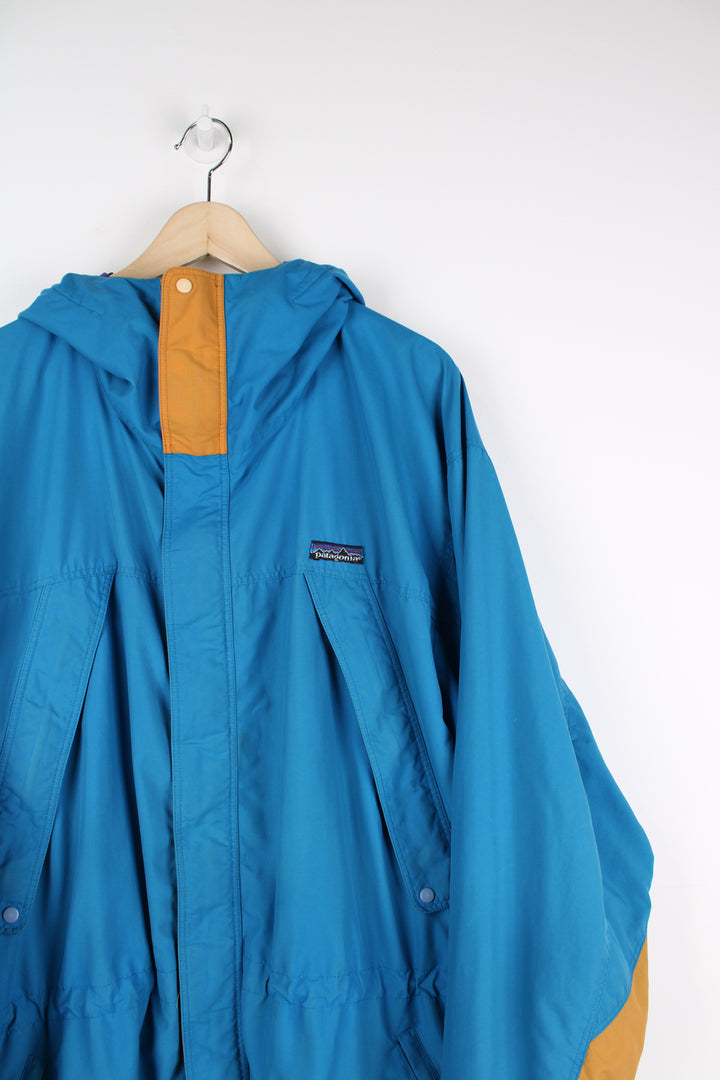 Patagonia Torrentshell outdoor jacket in blue, zip up, multiple pockets, hooded and has embroidered logo on the front.