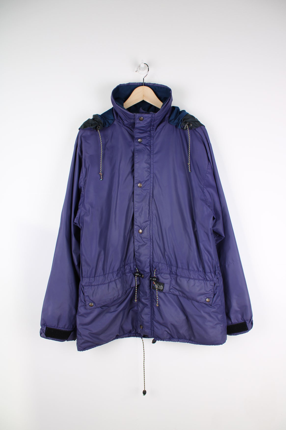 Vintage Rab Downpour waterproof jacket in purple, zip up, multiple pockets, hooded and has logo embroidered on the front.