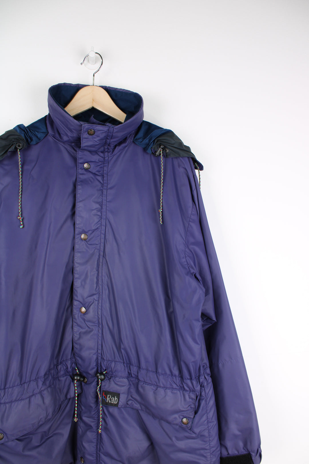 Vintage Rab Downpour waterproof jacket in purple, zip up, multiple pockets, hooded and has logo embroidered on the front.