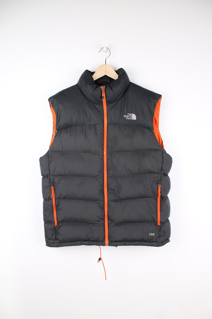 The North Face Face puffer gilet in a grey and orange, zip up with side pockets, insulated and has logo embroidered logo on the front and back.