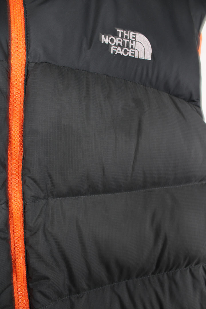 The North Face Face puffer gilet in a grey and orange, zip up with side pockets, insulated and has logo embroidered logo on the front and back.