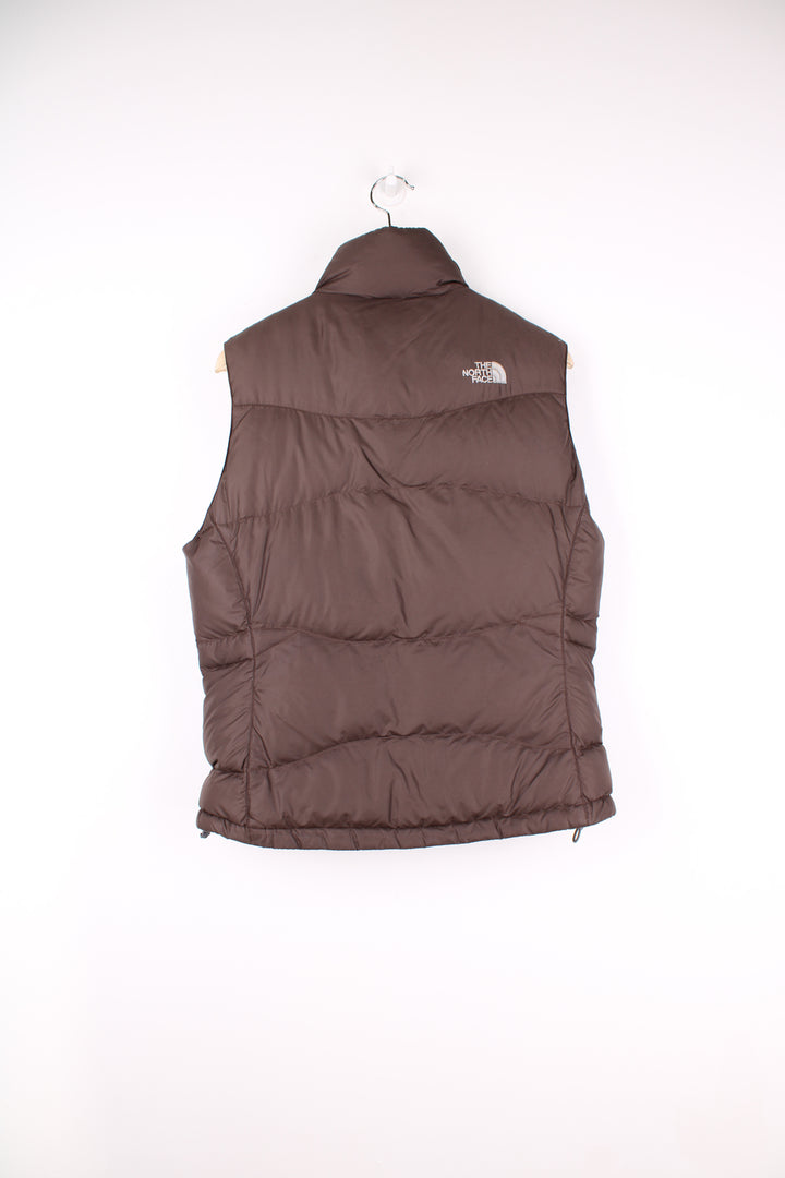 The North Face Face puffer gilet in brown, zip up with side pockets, insulated and has logo embroidered logo on the front and back.