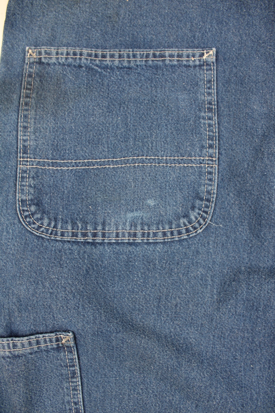 Carhartt Carpenter Jeans in a blue colourway with white cross stitching throughout, multiple pockets, and has the logo embroidered on the back pocket.