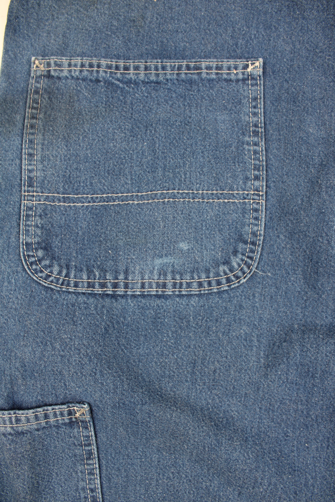 Carhartt Carpenter Jeans in a blue colourway with white cross stitching throughout, multiple pockets, and has the logo embroidered on the back pocket.