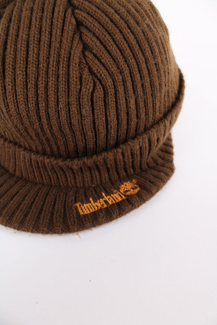 Timberland beanie cap in brown, features orange embroidered logo on the peak and on the back, one size.