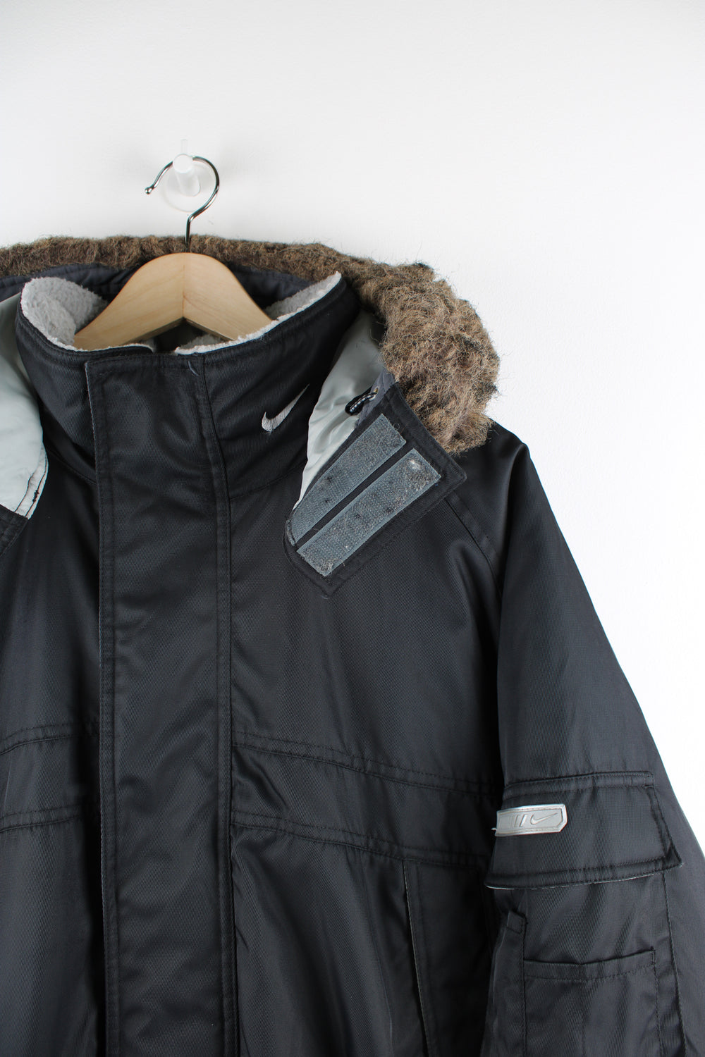 Vintage Nike Parka Coat in black, zip up, multiple pockets, detachable hood, fleece lining, and has swoosh logo embroidered on the front and back. 