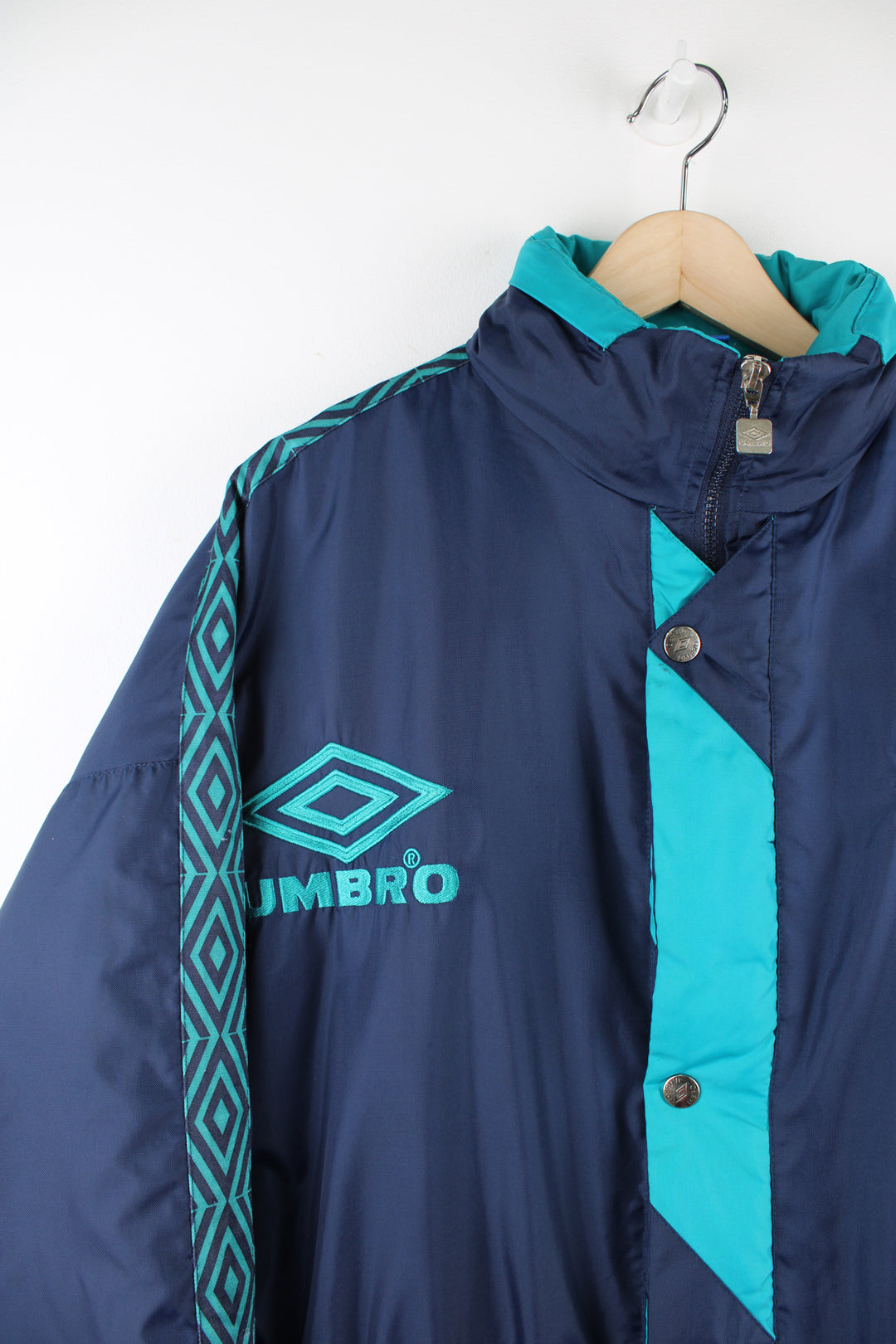 Vintage Umbro sports coats in a blue and green colourway, zip up, multiple pockets, insulated, has a hidden hood, adjustable and has logo embroidered on the front.