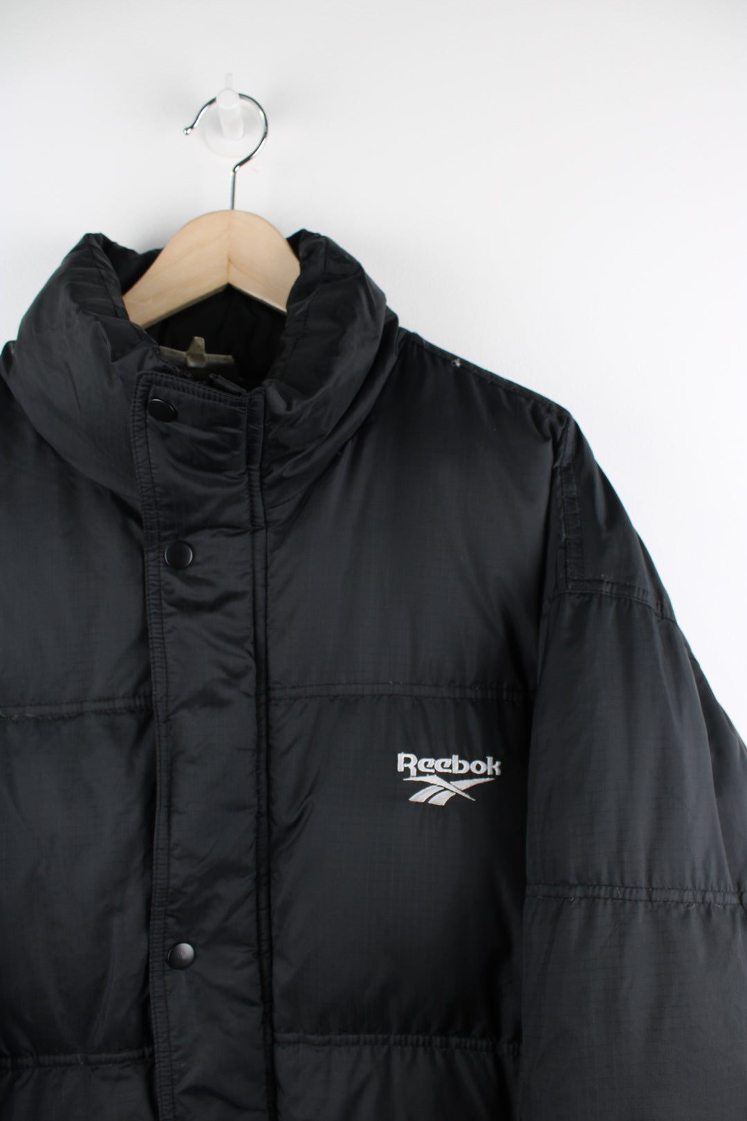 Vintage Reebok puffer jacket in black, zip up, insulated, side pockets and has the logo spell-out embroidered on the front and back.