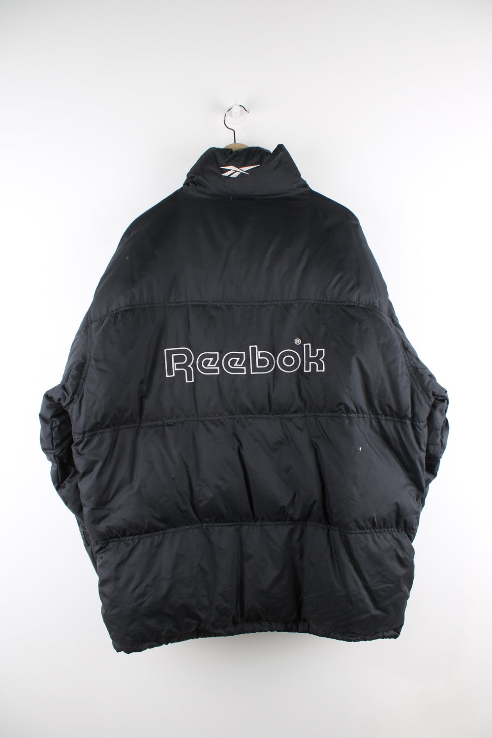 Vintage Reebok puffer jacket in black, zip up, insulated, side pockets and has the logo spell-out embroidered on the front and back.