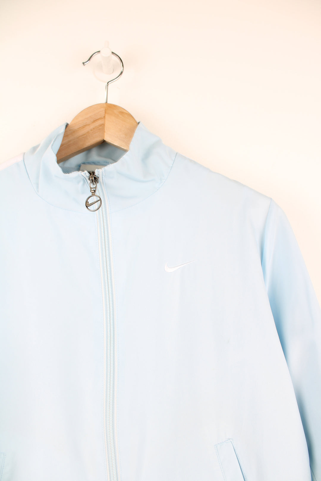 Nike Tracksuit Jacket in a blue and white colourway, zip up, side pockets, and has the swoosh logo embroidered on the front.