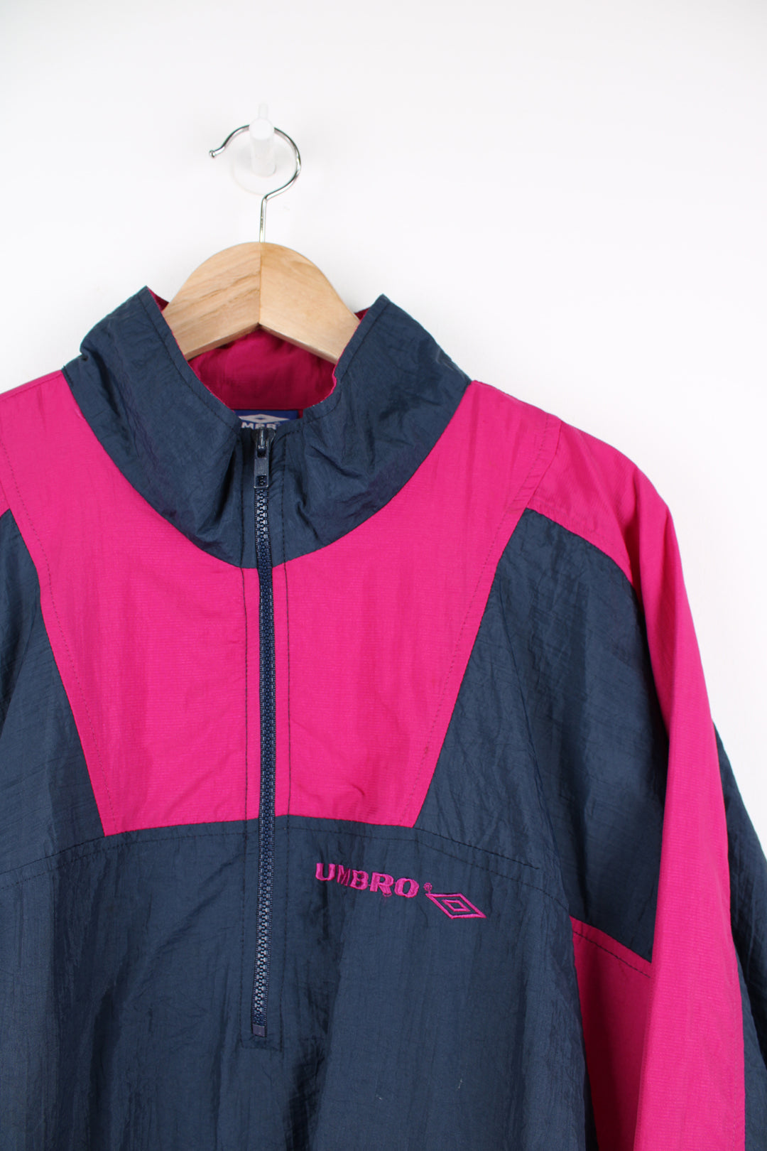 Vintage Umbro Pullover Windbreaker in a navy blue and pink colourway, half zip, side pockets, and has the logo embroidered on the front.