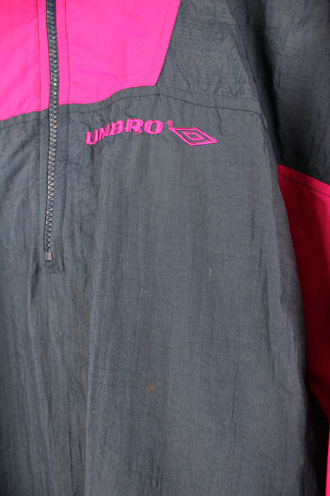 Vintage Umbro Pullover Windbreaker in a navy blue and pink colourway, half zip, side pockets, and has the logo embroidered on the front.