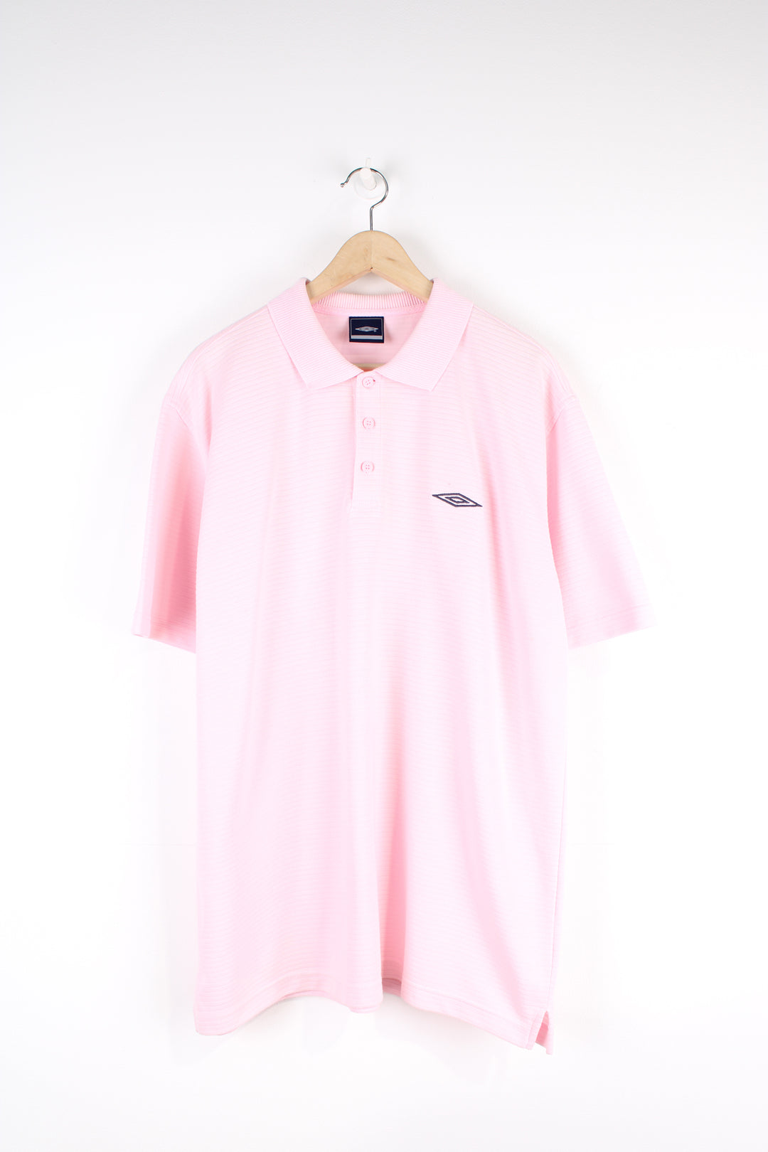 Vintage Umbro polo shirt in pink, button up with a collar, striped fabric, and has the logo embroidered on the chest.