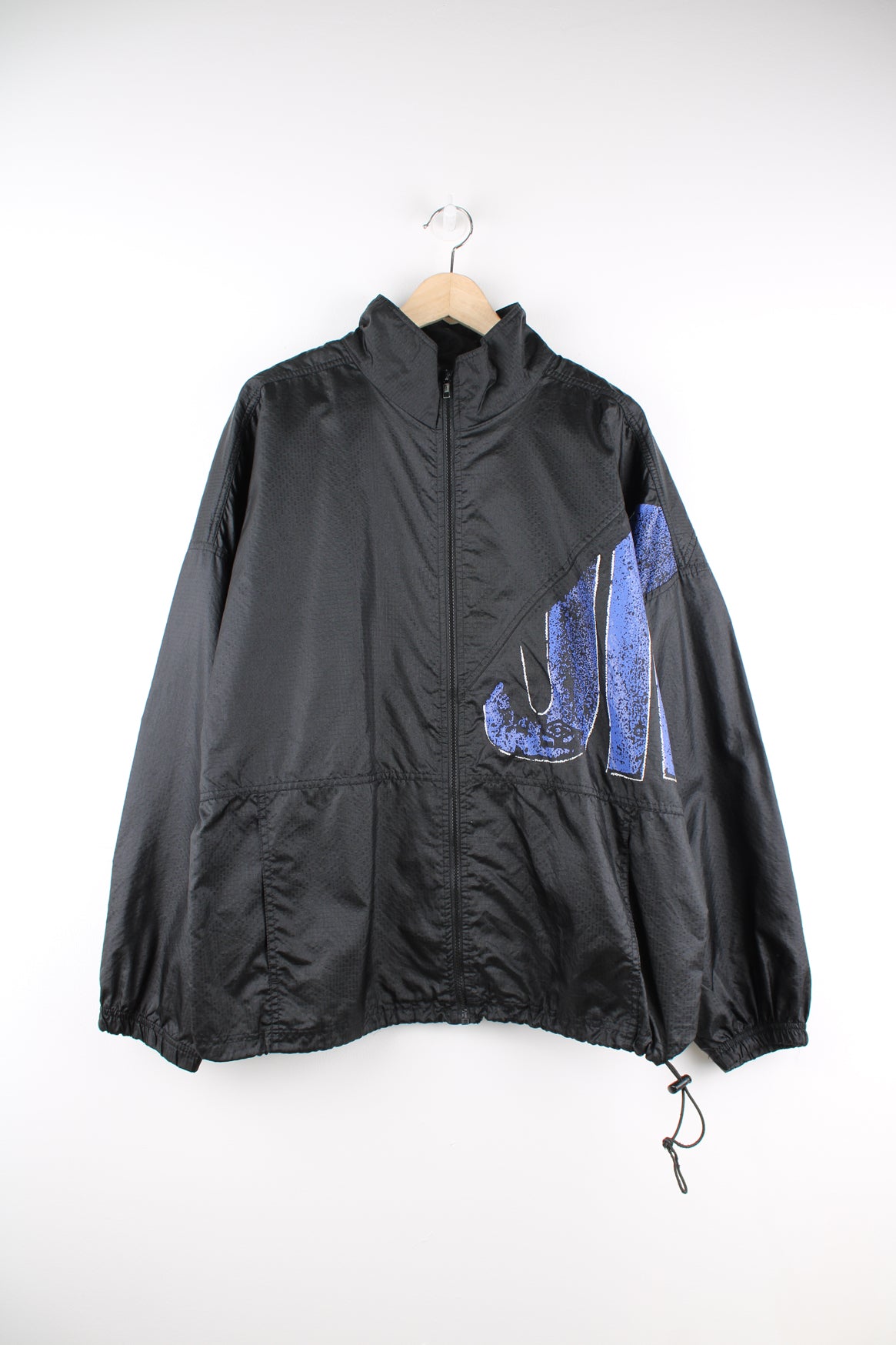 Umbro Windbreaker in a black and blue colourway, zip up, side pockets, and has the logo spell out printed across the front and back.