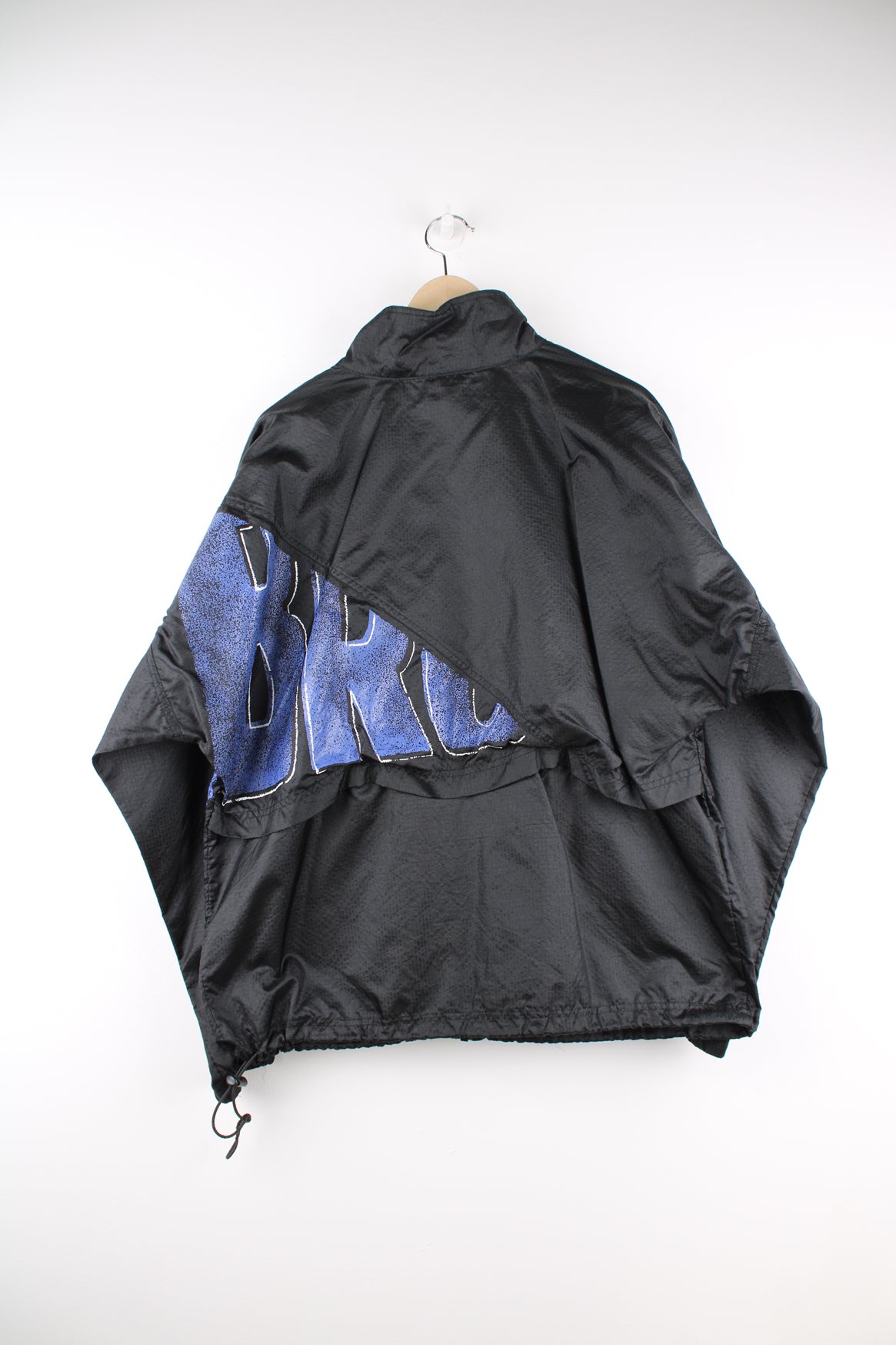 Umbro Windbreaker in a black and blue colourway, zip up, side pockets, and has the logo spell out printed across the front and back.