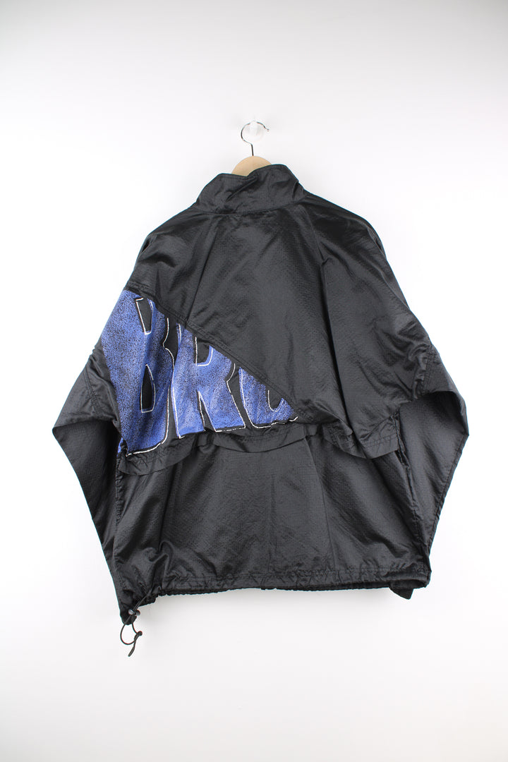 Umbro Windbreaker in a black and blue colourway, zip up, side pockets, and has the logo spell out printed across the front and back.