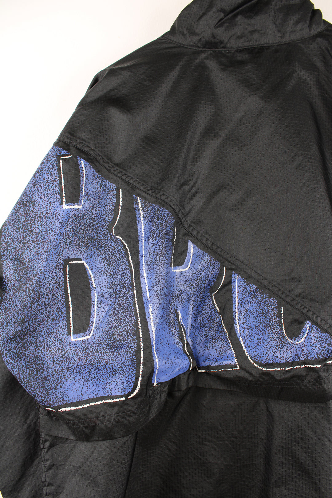 Umbro Windbreaker in a black and blue colourway, zip up, side pockets, and has the logo spell out printed across the front and back.