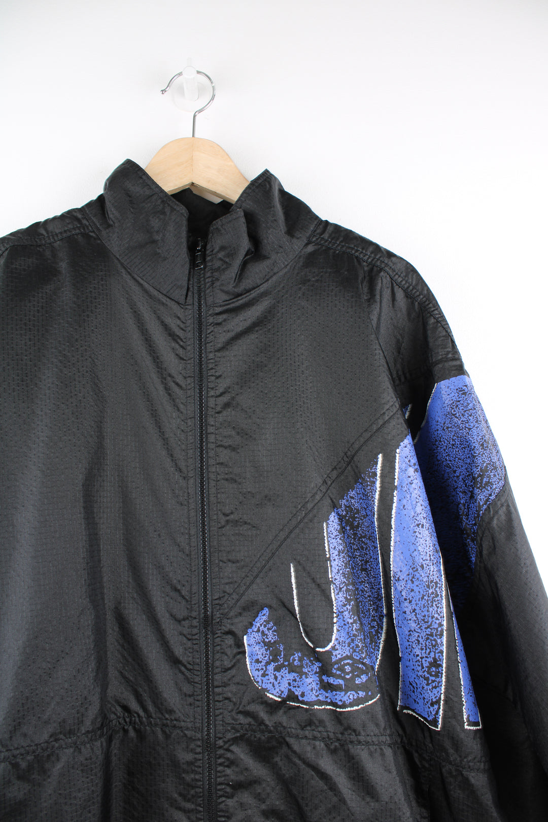 Umbro Windbreaker in a black and blue colourway, zip up, side pockets, and has the logo spell out printed across the front and back.