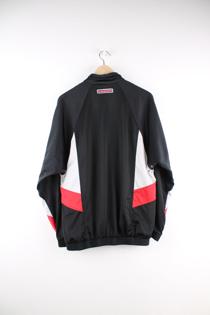 Umbro Tracksuit Jacket in a black, red and white colourway, zip up, side pockets, and has the logo embroidered on the front and back.