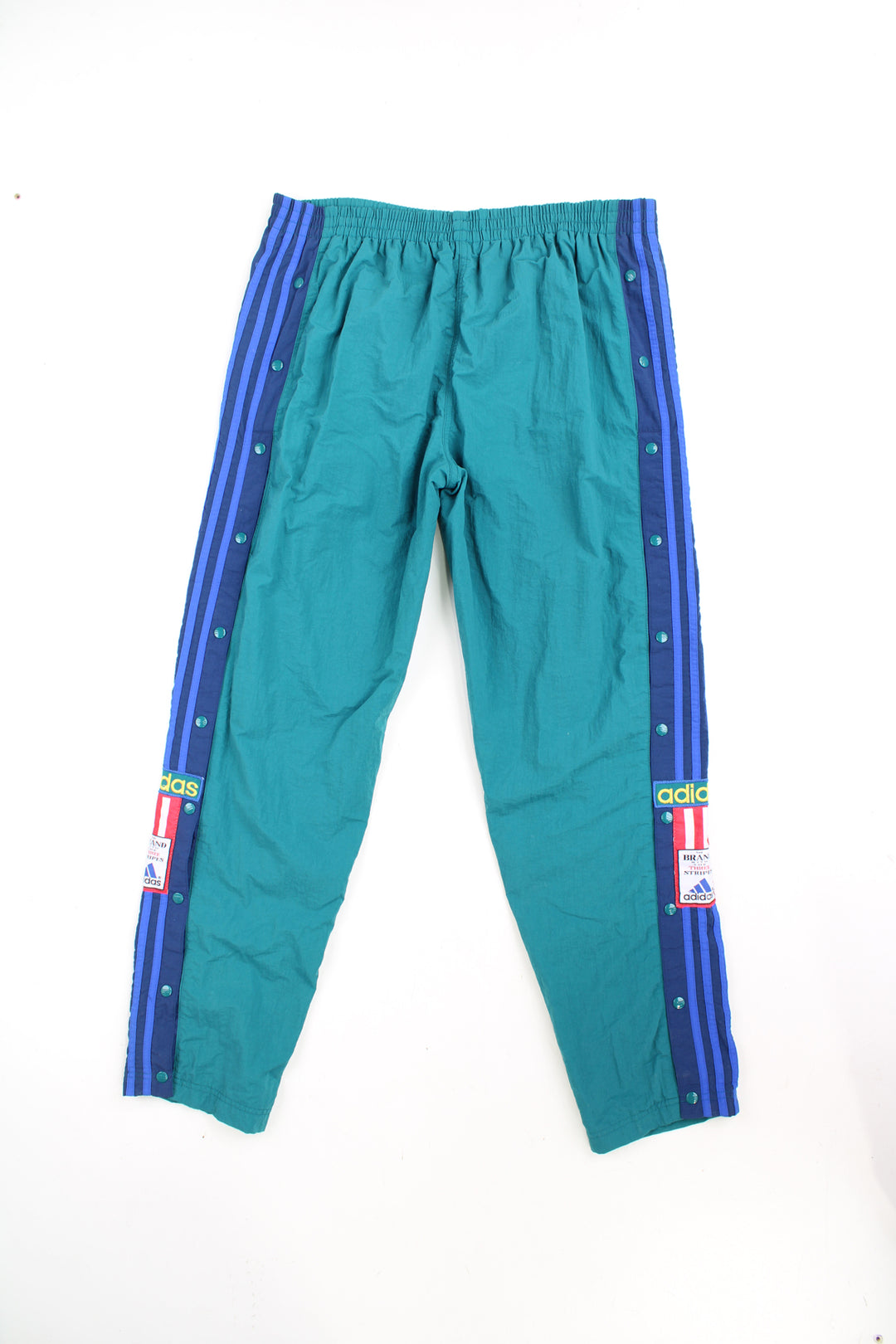 Vintage 90's Adidas tracksuit bottoms in turquoise blue with elasticated waistband and popper buttons down the legs. They also feature embroidered logos and three stripe detail. good condition Size in Label: 39 / 41 - Measure like a Mens XXL