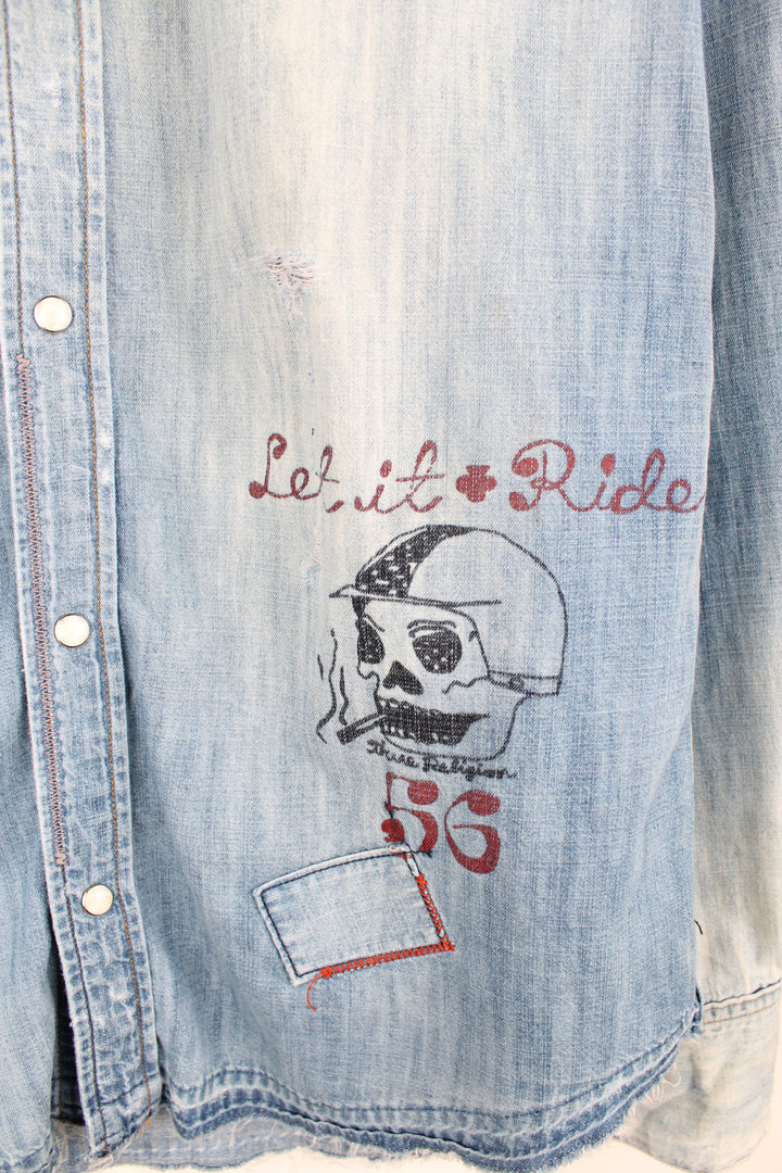 True Religion light wash heavily distressed denim shirt features embroidered badge and printed traditonal tattoo style graphics all over 