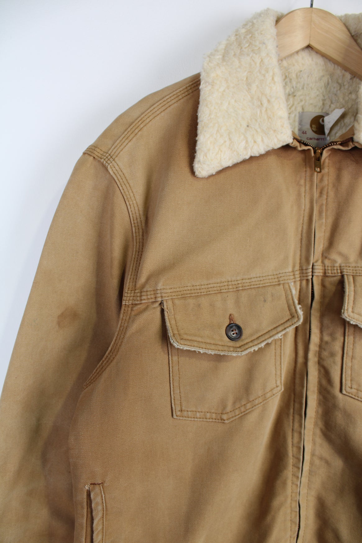 Vintage Carhartt Sherpa Workwear Jacket, in a tan colourway, sherpa lining and collar, multiple pockets, and has embroidered Carhartt logo on the front.