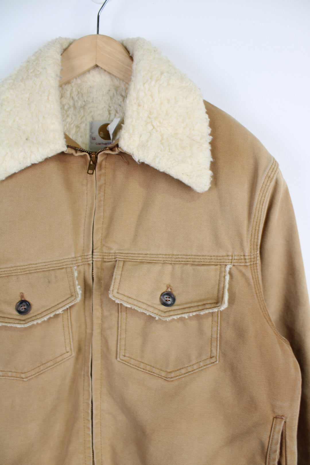 Vintage Carhartt Sherpa Workwear Jacket, in a tan colourway, sherpa lining and collar, multiple pockets, and has embroidered Carhartt logo on the front.